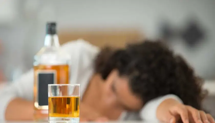 Szklanka z alkoholem i butelka obok śpiącej osoby. Nie ma sposobu, jak sprawdzić promile bez alkomatu.