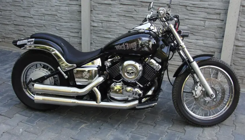 Czarny motocykl Yamaha Drag Star 650 z ozdobami czaszek. Pojemność baku pozwala na długie podróże.