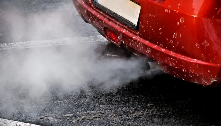 Z rury wydechowej czerwonego auta wydobywa się biały dym, jakby rozbiegany diesel próbował złapać oddech.