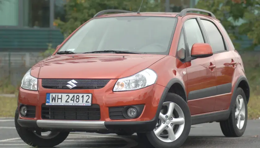 Pomarańczowy Suzuki SX4 z przodu, z widoczną tablicą rejestracyjną.