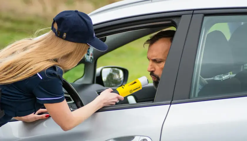 Policjantka bada alkomatem kierowcę. To jeden z przypadków, kiedy policja może badać alkomatem.