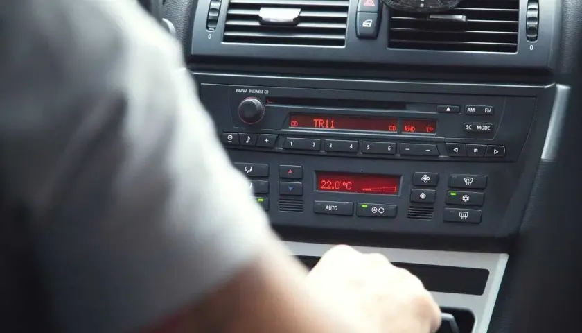 Ręka kierowcy manipuluje przy radiu BMW, pokazując jak ustawić radio w samochodzie. Widoczna temperatura 22°C.