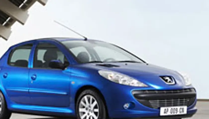 Niebieski Peugeot 206 1.1 stoi na tle nowoczesnej architektury.