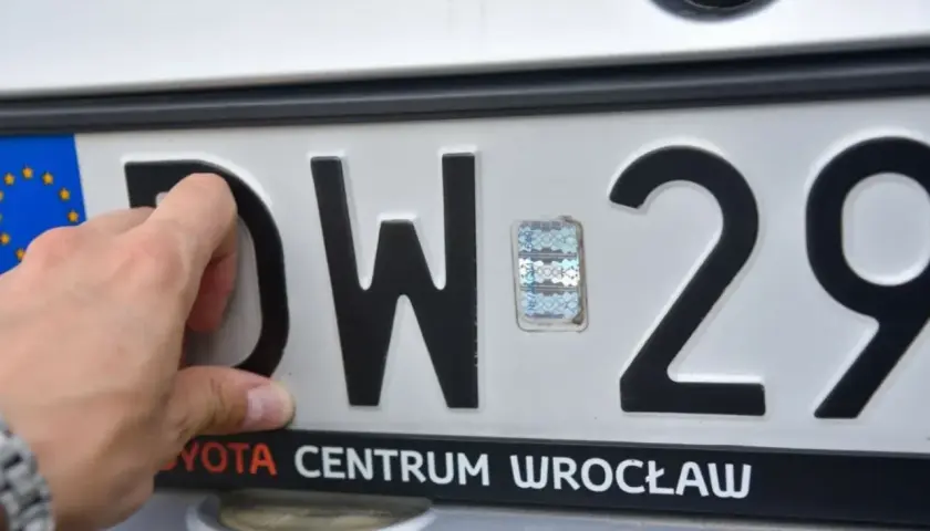 Dłoń poprawia hologram na tablicy rejestracyjnej DW 29. Toyota Centrum Wrocław.