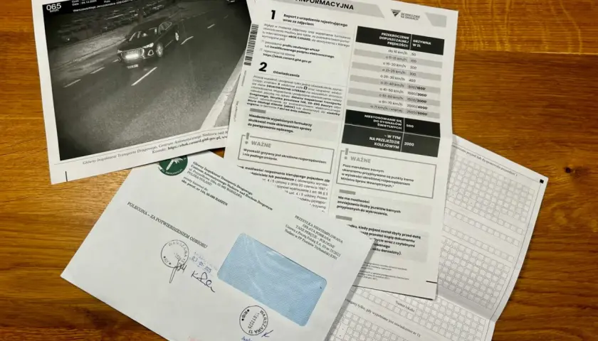 Dokumenty dotyczące wykroczenia drogowego i informacji, jak przedłużyć kartę kierowcy. Widoczny jest raport z fotoradaru, formularz informacyjny oraz koperta.