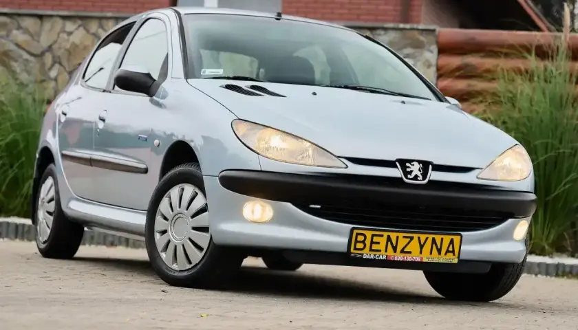 Jasny Peugeot 206 1.4 benzyna z żółtą tablicą rejestracyjną "BENZYNA" stoi na zewnątrz.