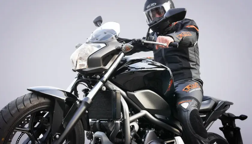 Motocyklista w kasku i kombinezonie na czarnym motocyklu. Zastanawiasz się, jakie prawo jazdy na motor będzie potrzebne?