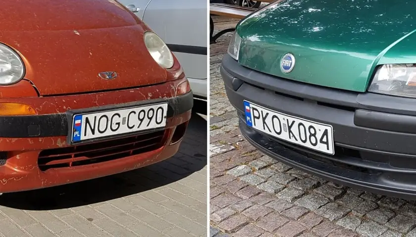 Dwa samochody, czerwony i zielony, z polskimi tablicami rejestracyjnymi. Na czerwonym NOG C990, na zielonym PKO K084.