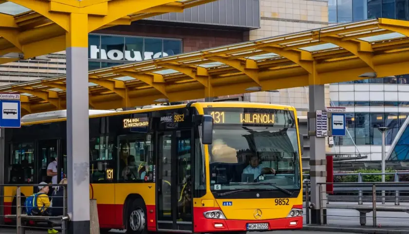Żółto-czerwony autobus miejski na przystanku. Kierowca autobusu PKS, jak i jego zarobki, to temat dyskusji, ale ten pojazd wozi pasażerów.