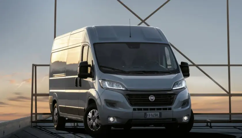 Szary Fiat Ducato na tle zachodzącego słońca. Zastanawiasz się nad pojemnością baku? Ten model oferuje duży zasięg.