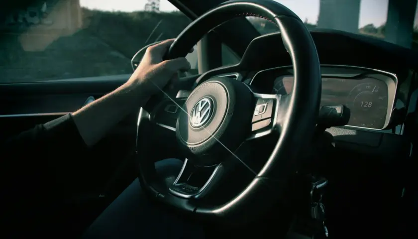 Ręka na kierownicy Volkswagena, na desce rozdzielczej widać prędkość 128 km/h. Zastanawiasz się, czy można sprzedać samochód z miękkim dowodem?