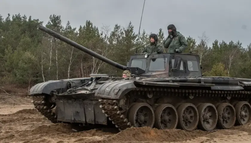 Szkolenie z zakresu jak zostać kierowcą czołgu. Trzech żołnierzy w wojskowych pojazdach, jeden z nich siedzi w otwartym włazie, dwóch innych w kabinie.