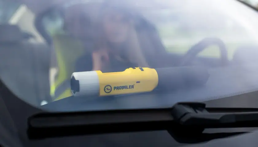 Żółty alkomat Promiler leży na desce rozdzielczej samochodu.