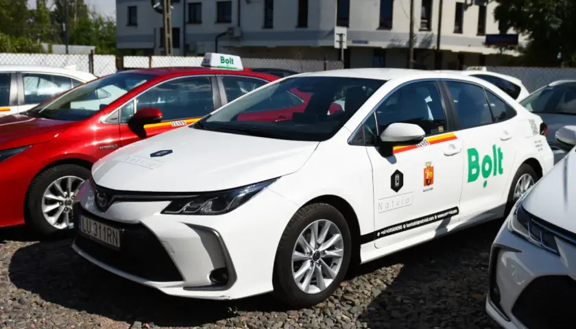 Białe i czerwone samochody z logo Bolt, gotowe do jazdy. Dowiedz się, jak zostać kierowcą Bolt i zacznij zarabiać.