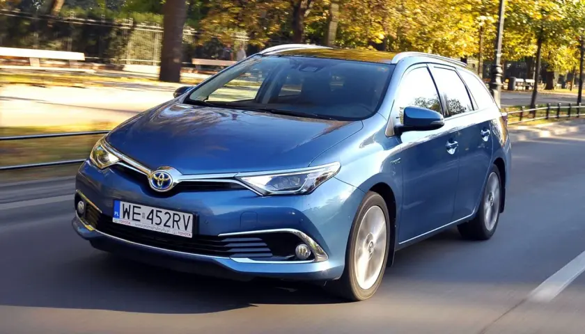 Niebieska Toyota Auris Hybrid kombi w ruchu ulicznym, jesienią.