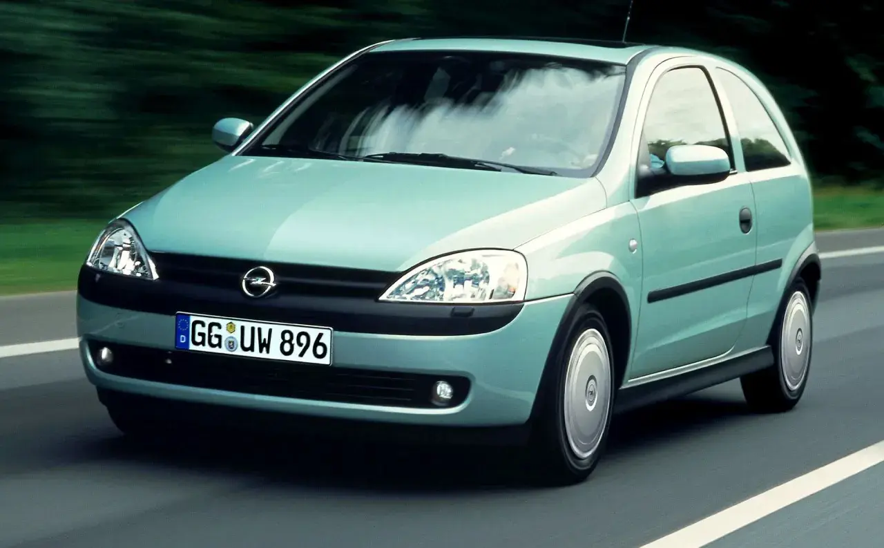 Jasnozielony Opel Corsa C na drodze, z widocznym logo i tablicą rejestracyjną.