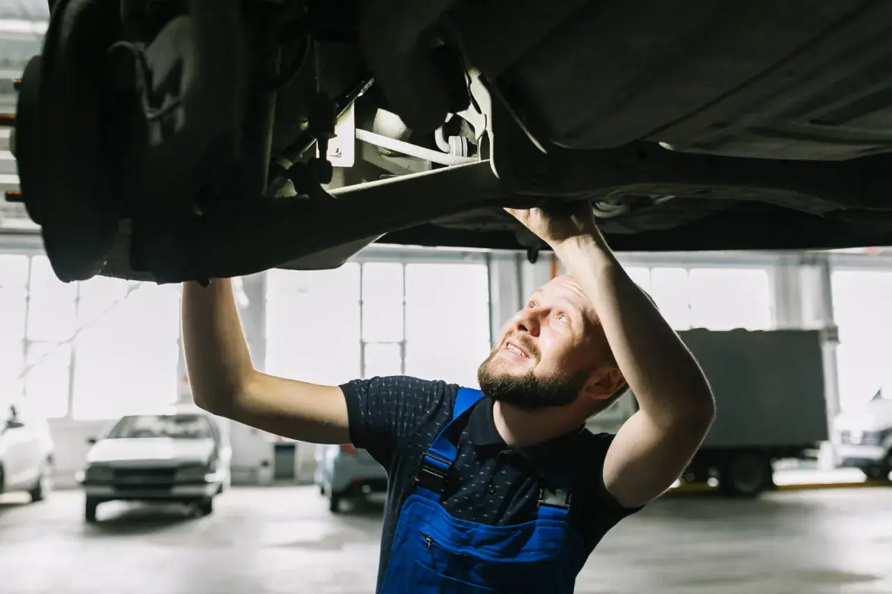 Mechanik sprawdza podwozie auta, szukając rozwiązań jak zwiększyć prześwit w samochodzie.