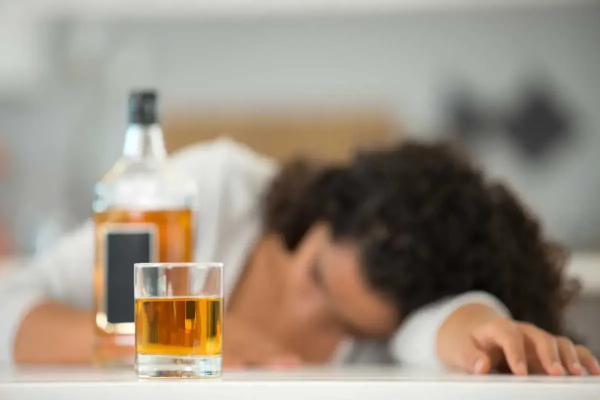 Szklanka z alkoholem i butelka obok śpiącej osoby. Nie ma sposobu, jak sprawdzić promile bez alkomatu.