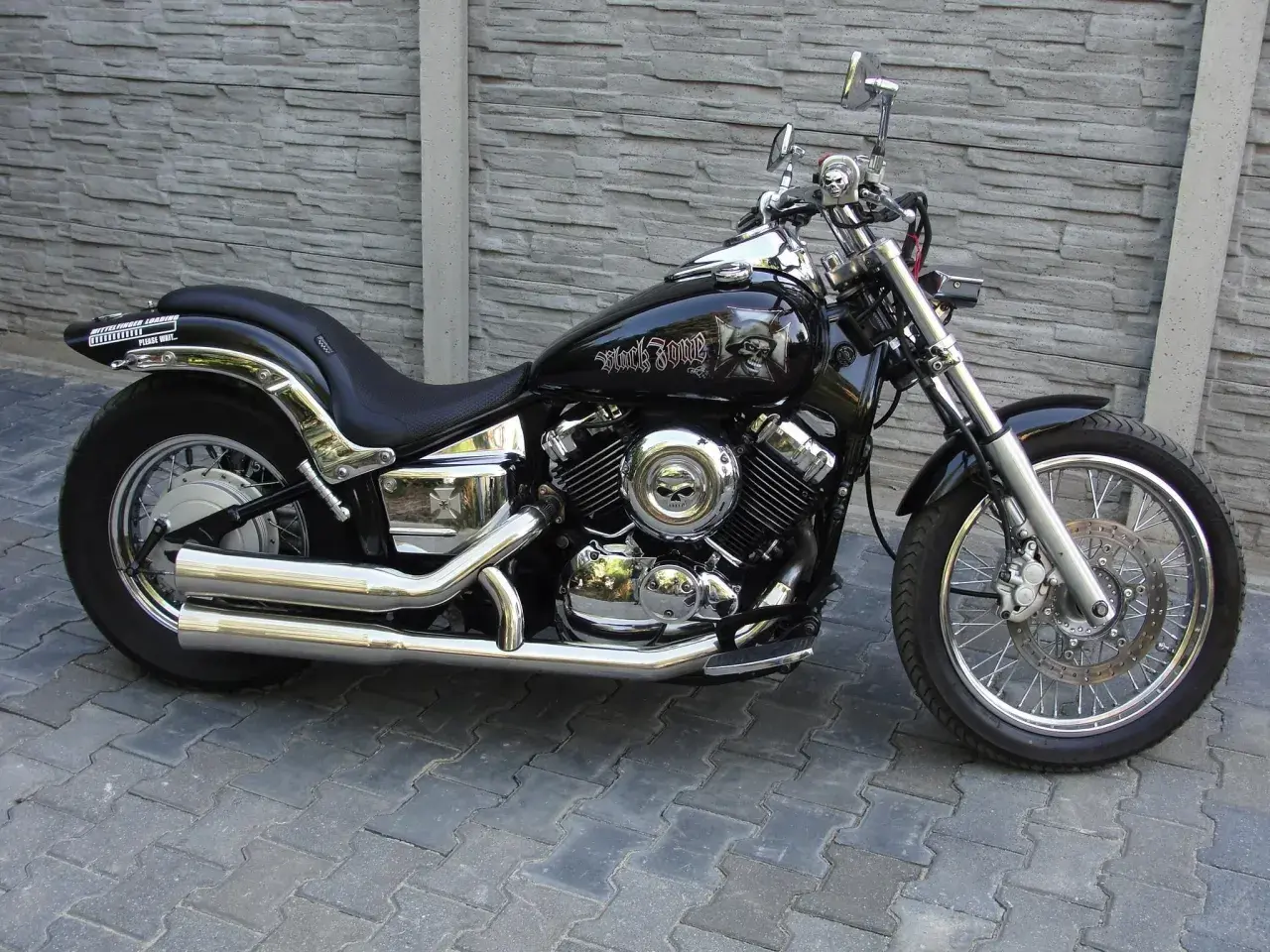 Czarny motocykl Yamaha Drag Star 650 z ozdobami czaszek. Pojemność baku pozwala na długie podróże.