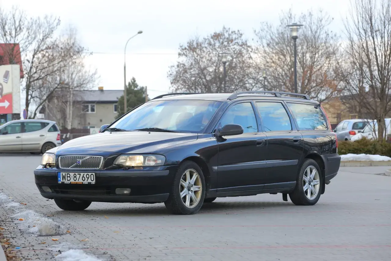 Ciemny czarny kombi Volvo V70 zaparkowany na zewnątrz.
