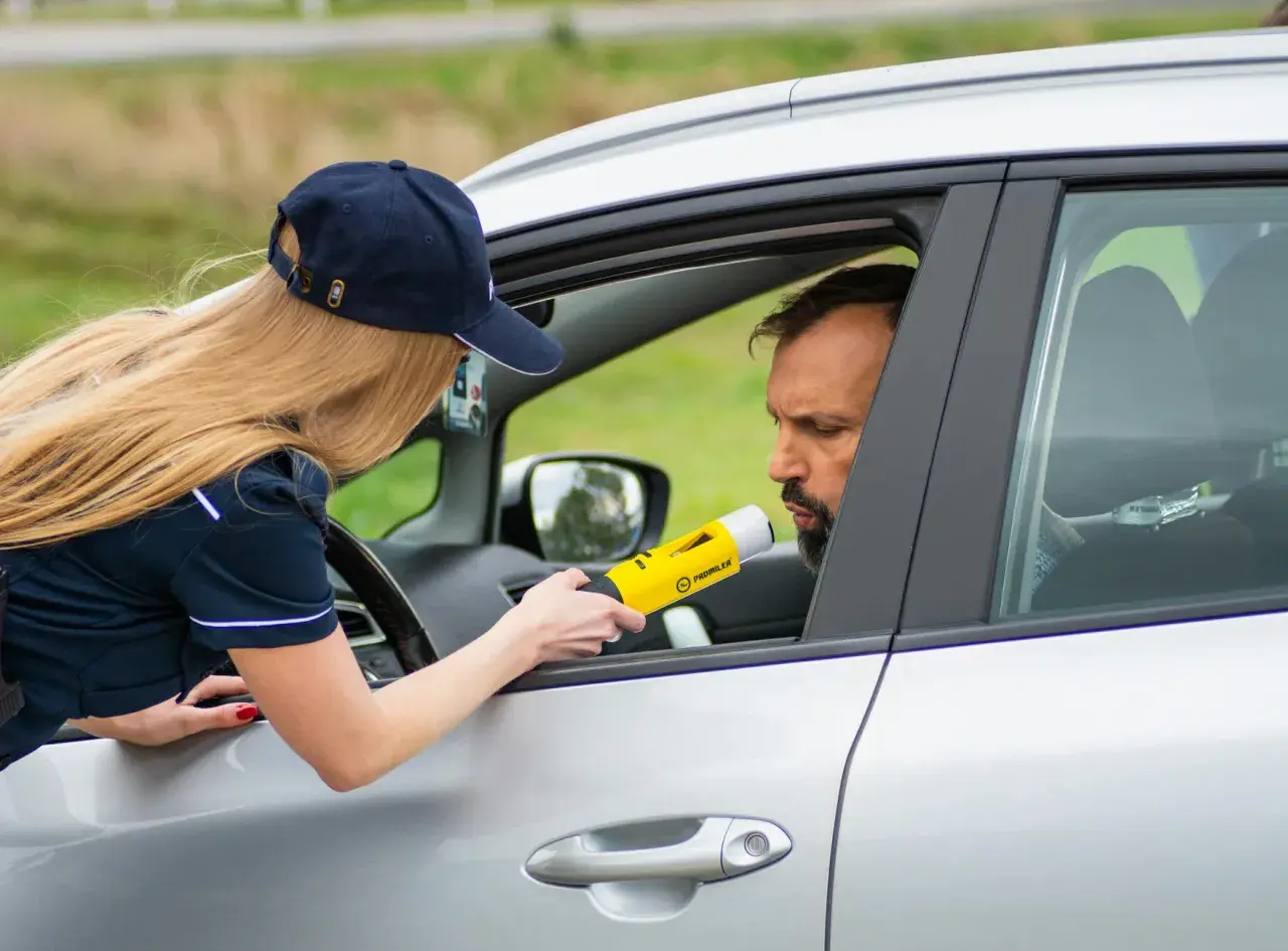 Policjantka bada alkomatem kierowcę. To jeden z przypadków, kiedy policja może badać alkomatem.