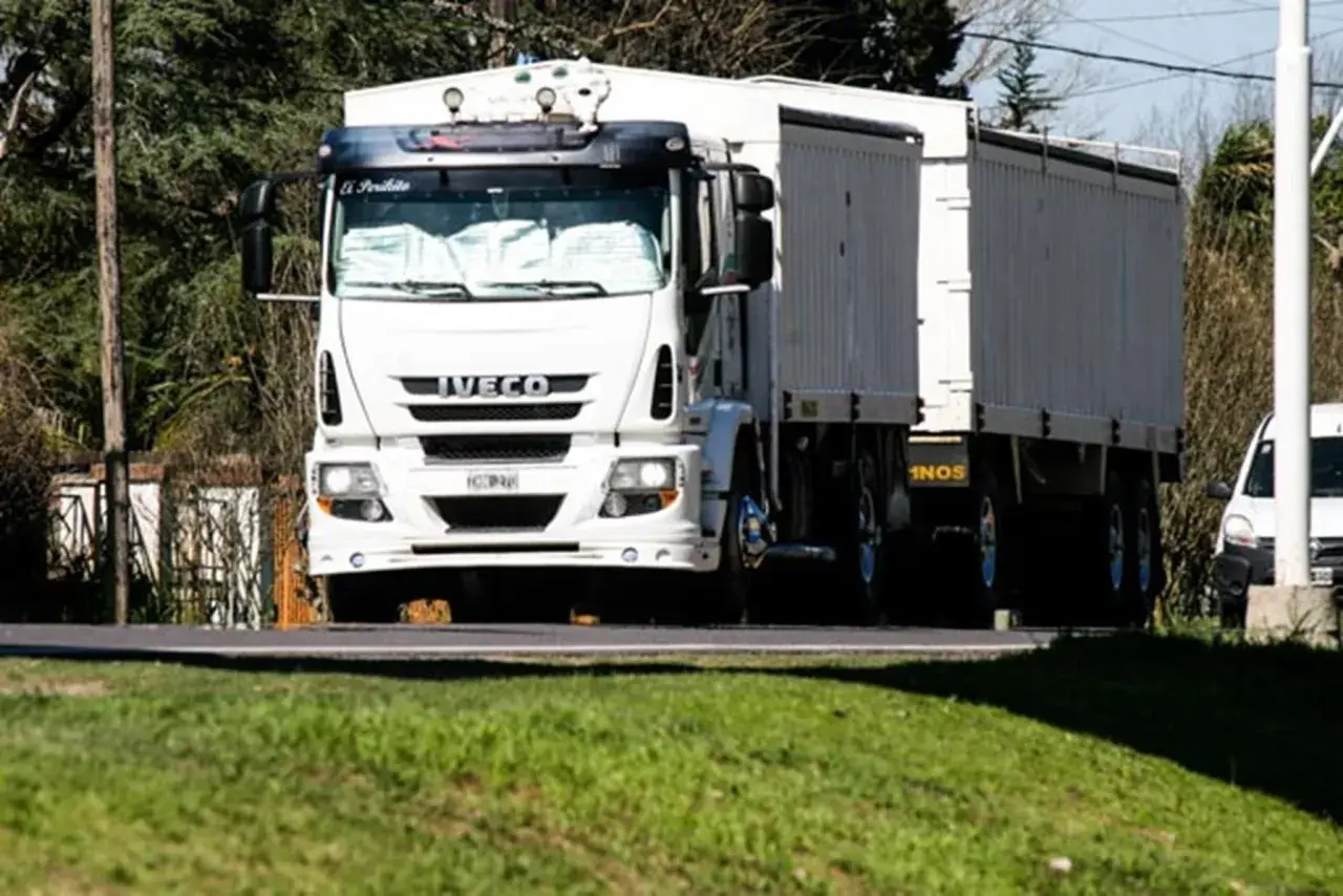 Biała ciężarówka Iveco z naczepą jedzie drogą. Kierowca ciężarówek wyrusza w długą trasę.