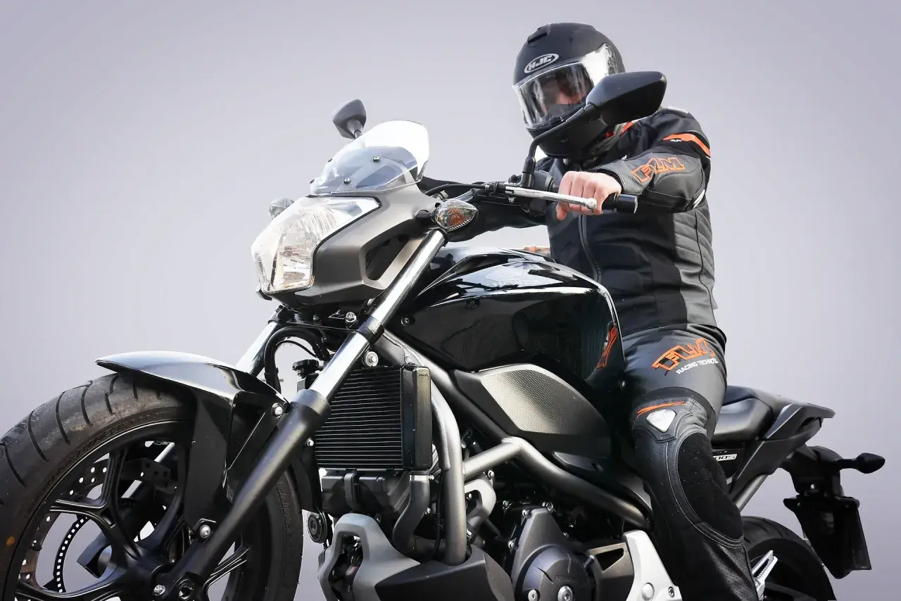 Motocyklista w kasku i kombinezonie na czarnym motocyklu. Zastanawiasz się, jakie prawo jazdy na motor będzie potrzebne?