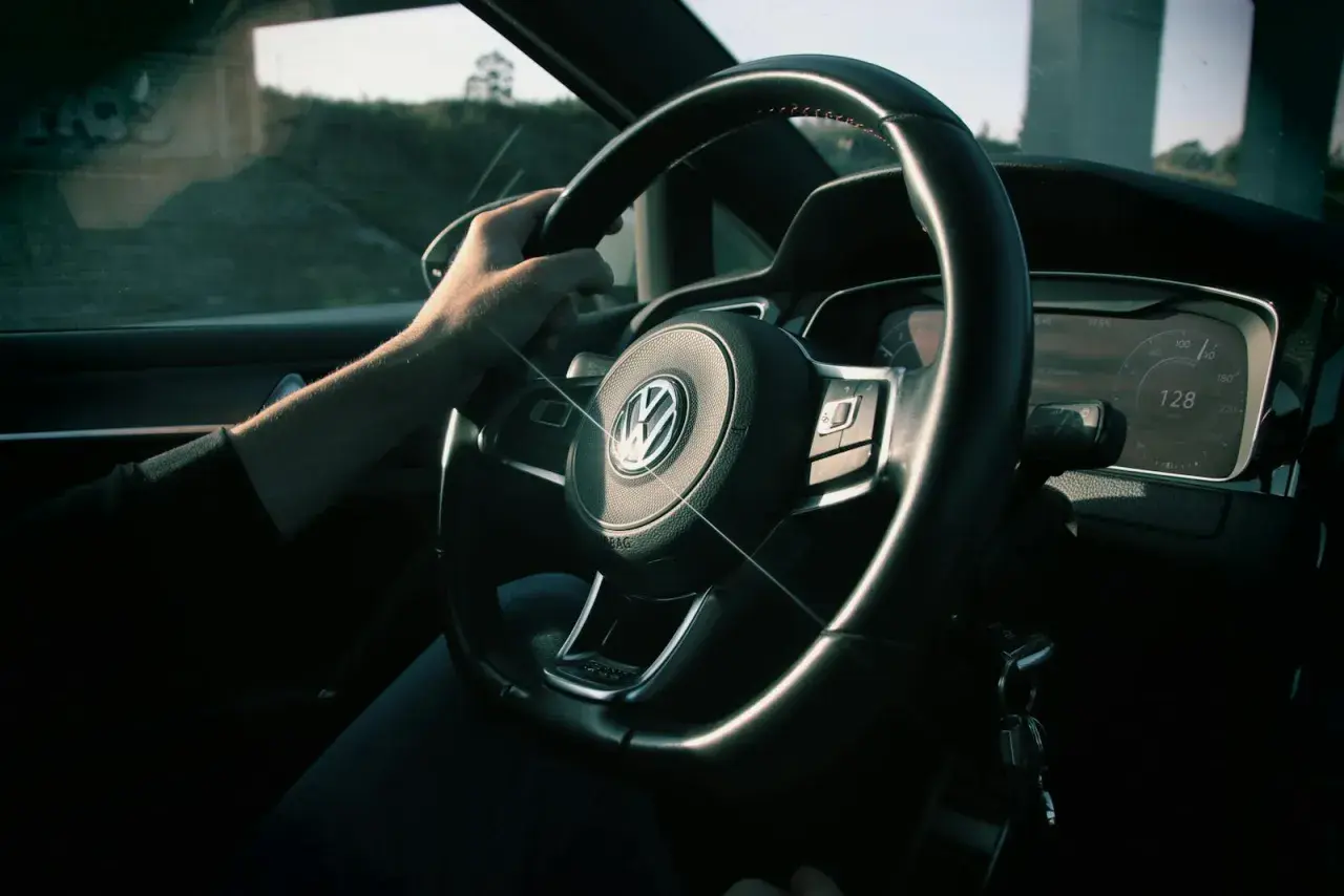 Ręka na kierownicy Volkswagena, na desce rozdzielczej widać prędkość 128 km/h. Zastanawiasz się, czy można sprzedać samochód z miękkim dowodem?