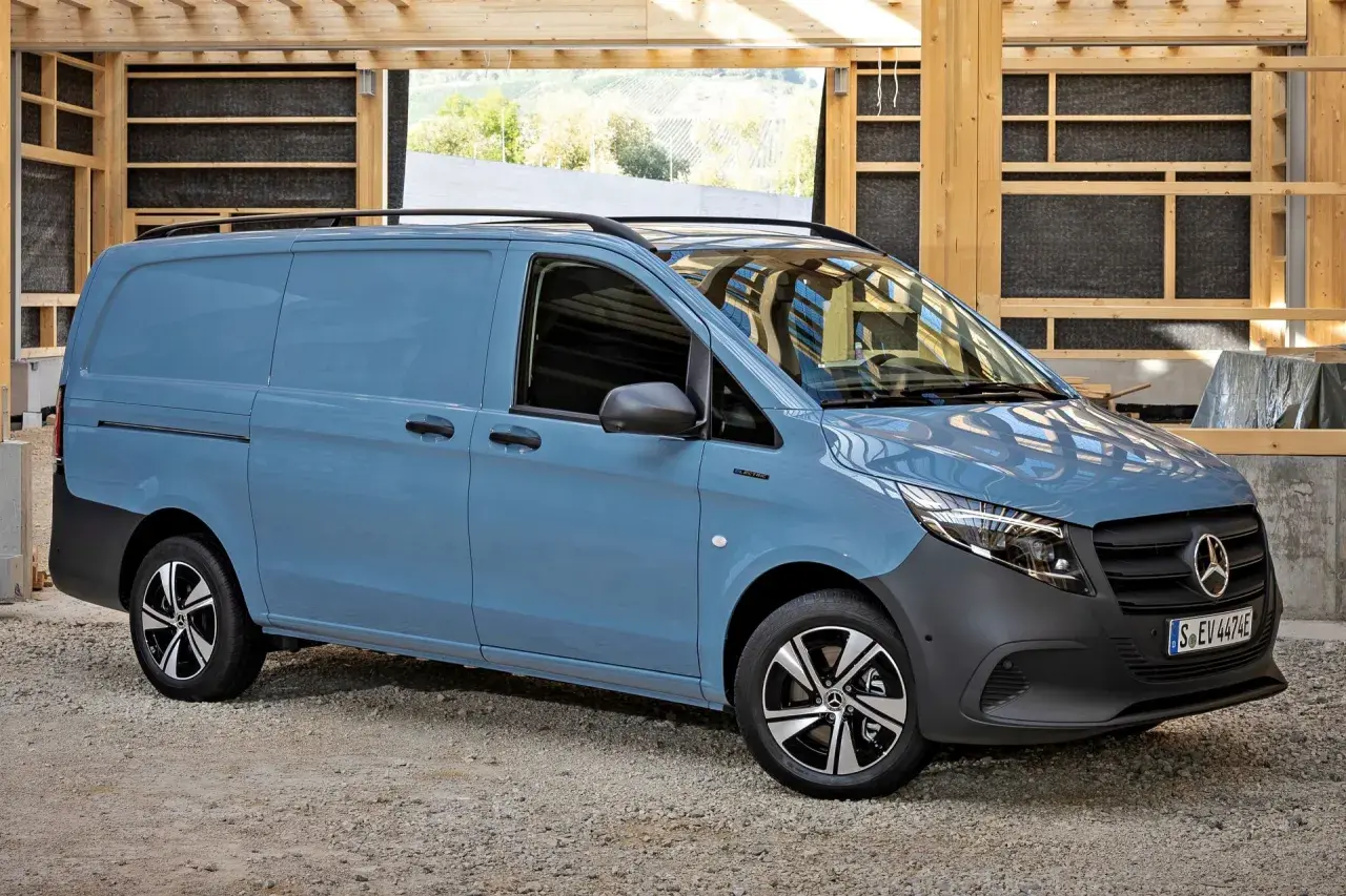 Niebieski Mercedes Vito stoi na żwirowym podłożu, w tle drewniana konstrukcja.