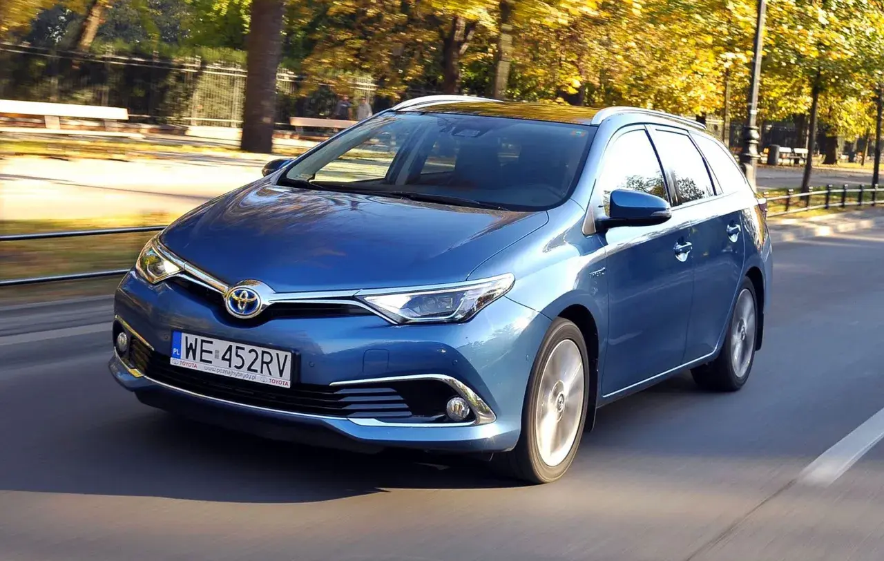 Niebieska Toyota Auris Hybrid kombi w ruchu ulicznym, jesienią.