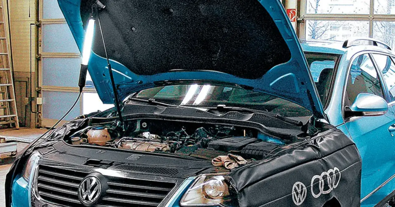 Mechanik pracuje przy silniku 2.0 TDI w niebieskim samochodzie. Maskę podniesiono, a pod nią widać elementy silnika i narzędzia.