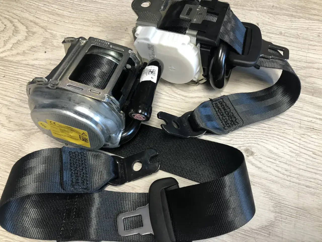 Dwa zwinięte pasy bezpieczeństwa z mechanizmami zwijającymi. Zastanawiasz się, ile kosztuje wymiana pasów bezpieczeństwa?