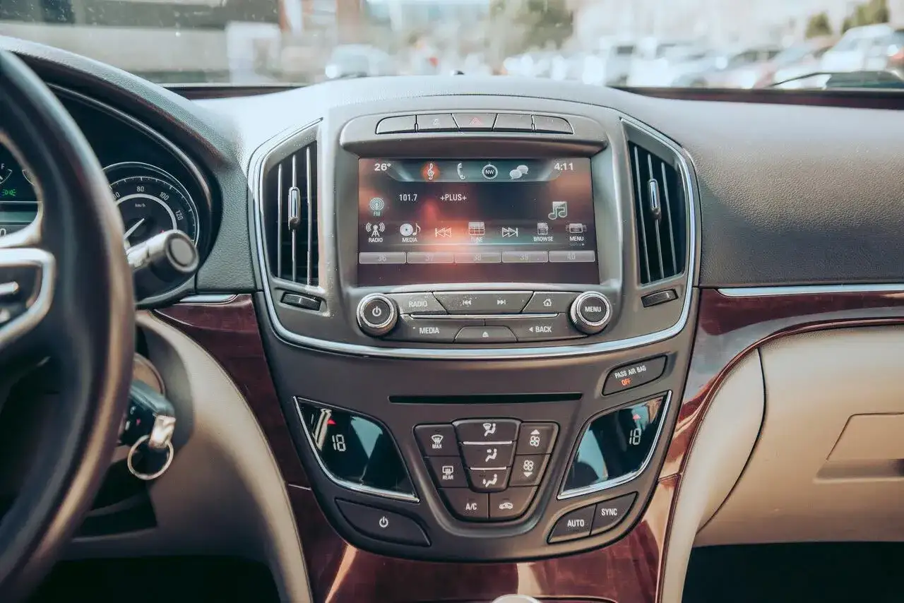Wnętrze Buick Regal z ekranem multimedialnym, klimatyzacją i drewnianymi wstawkami.