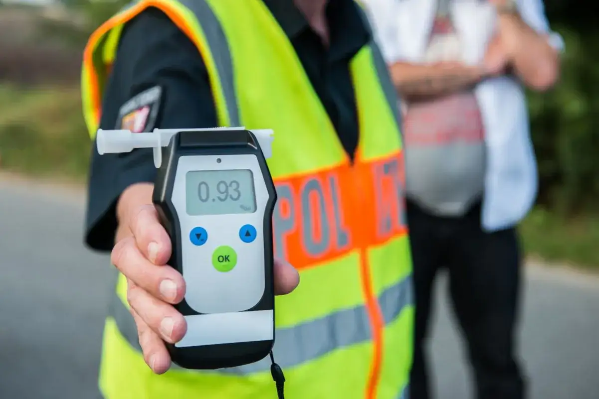 Policjant pokazuje alkomat z wynikiem 0.93 promila. Urządzenie służy do pomiaru stężenia alkoholu w wydychanym powietrzu.