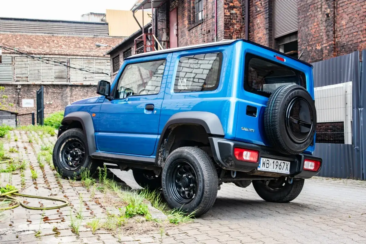 Niebieski Suzuki Jimny z zapasowym kołem z tyłu. Zastanawiasz się nad pojemnością baku? Ten model jest gotowy na przygodę.
