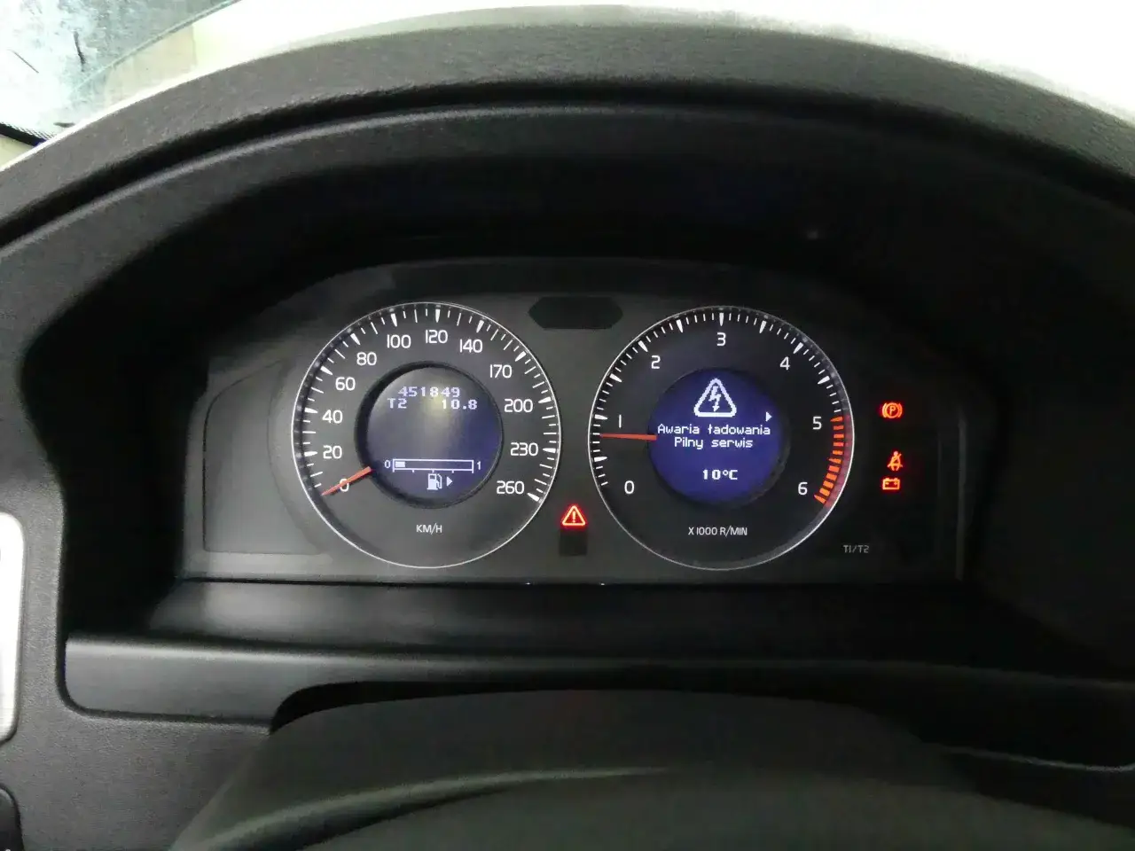Wskaźnik paliwa w Volvo V70 pokazuje prawie pełny bak. Obok komunikat o awarii ładowania.