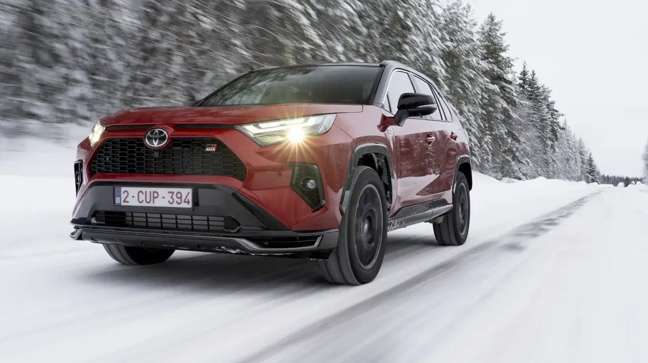 Czerwony Toyota RAV4 GR Sport przemierza ośnieżoną drogę. Zastanawiasz się nad jego pojemnością baku?