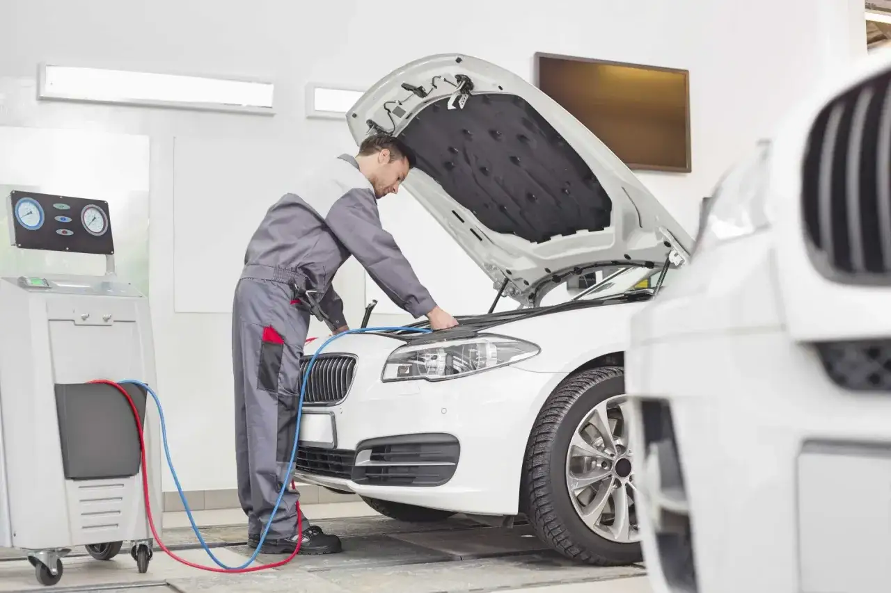 Mechanik sprawdza auto, zastanawiasz się, ile kosztuje przegląd samochodowy? Na zdjęciu widać serwis.
