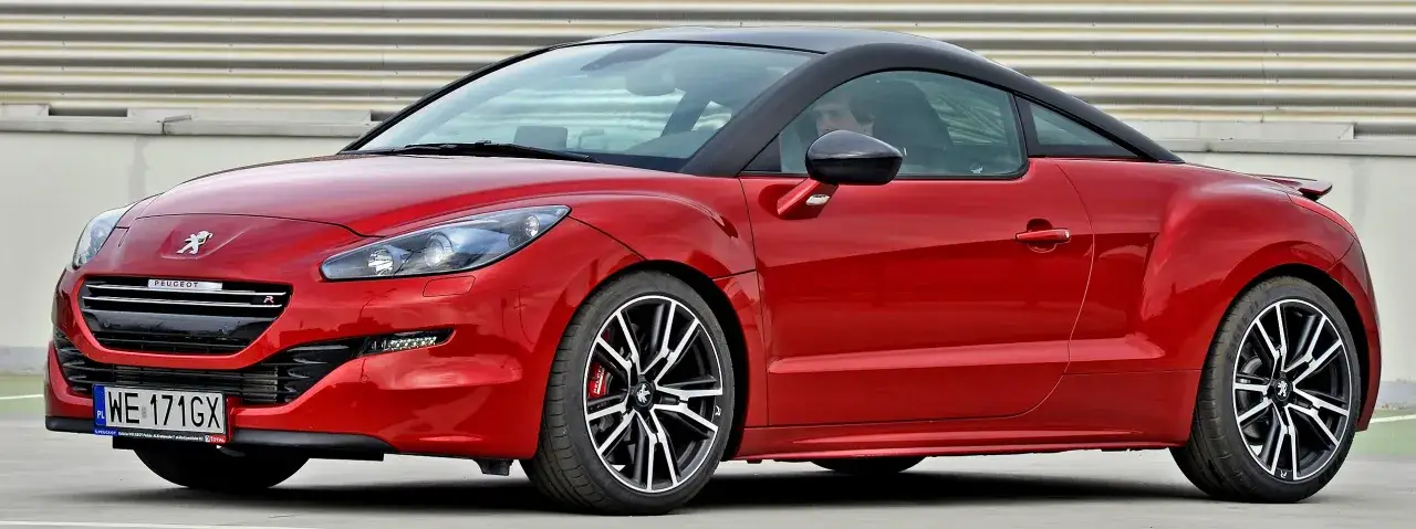 Czerwone coupe Peugeot RCZ z czarnym dachem i felgami, gotowe do dynamicznej jazdy.