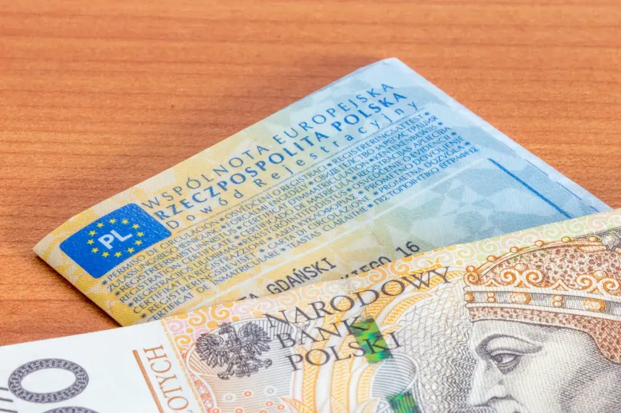 Dowód rejestracyjny i banknot 100 zł. Zastanawiasz się, ile kosztuje rejestracja samochodu?
