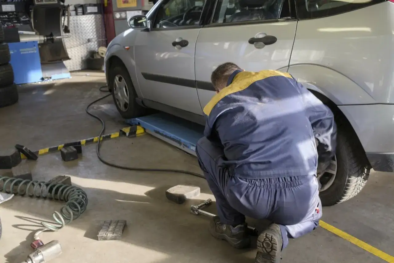 Mechanik w warsztacie samochodowym pracuje przy aucie. Zastanawiasz się, ile zarabia kierowca mechanik?
