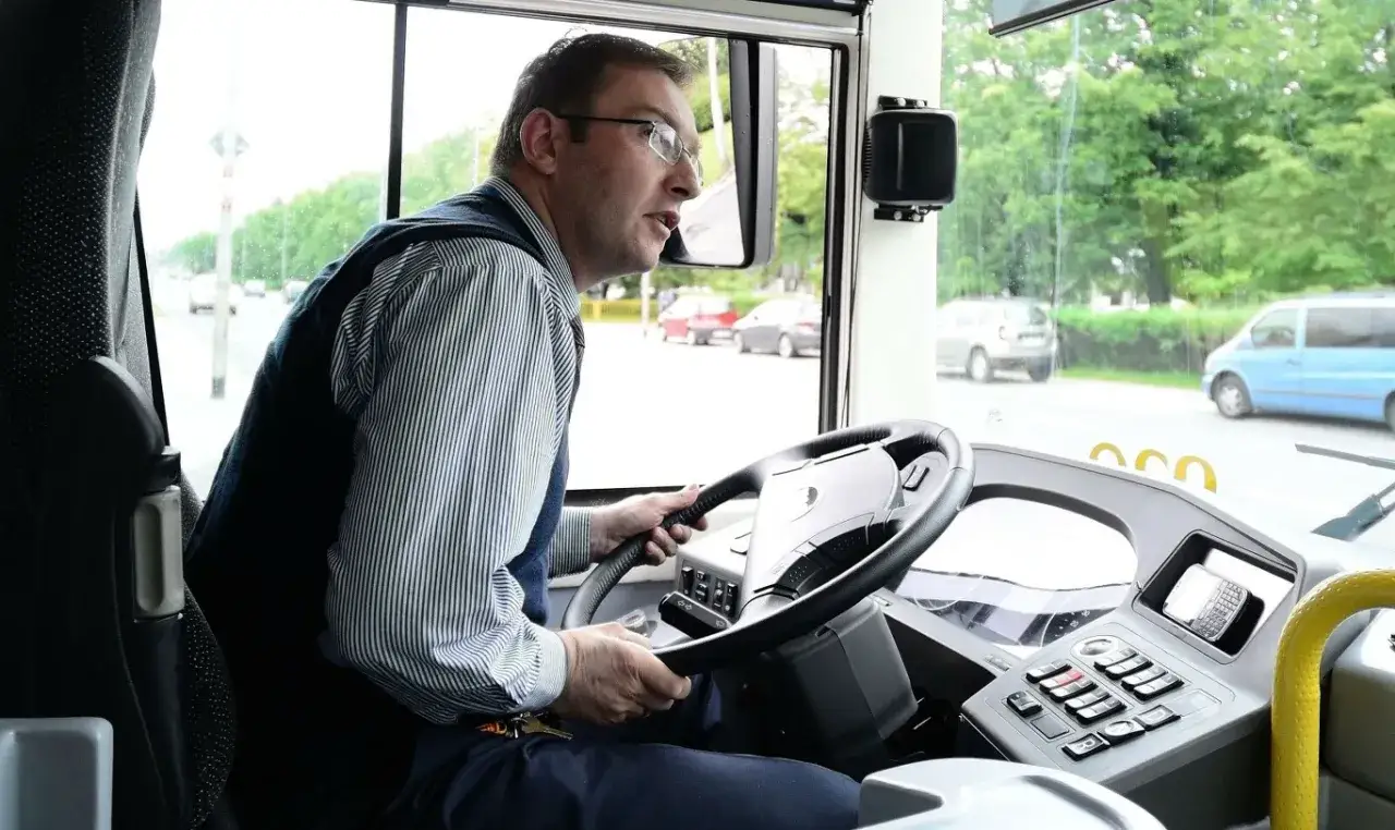 Kierowca autobusu za kierownicą, zastanawia się, ile zarabia kierowca autobusu, patrząc na drogę.