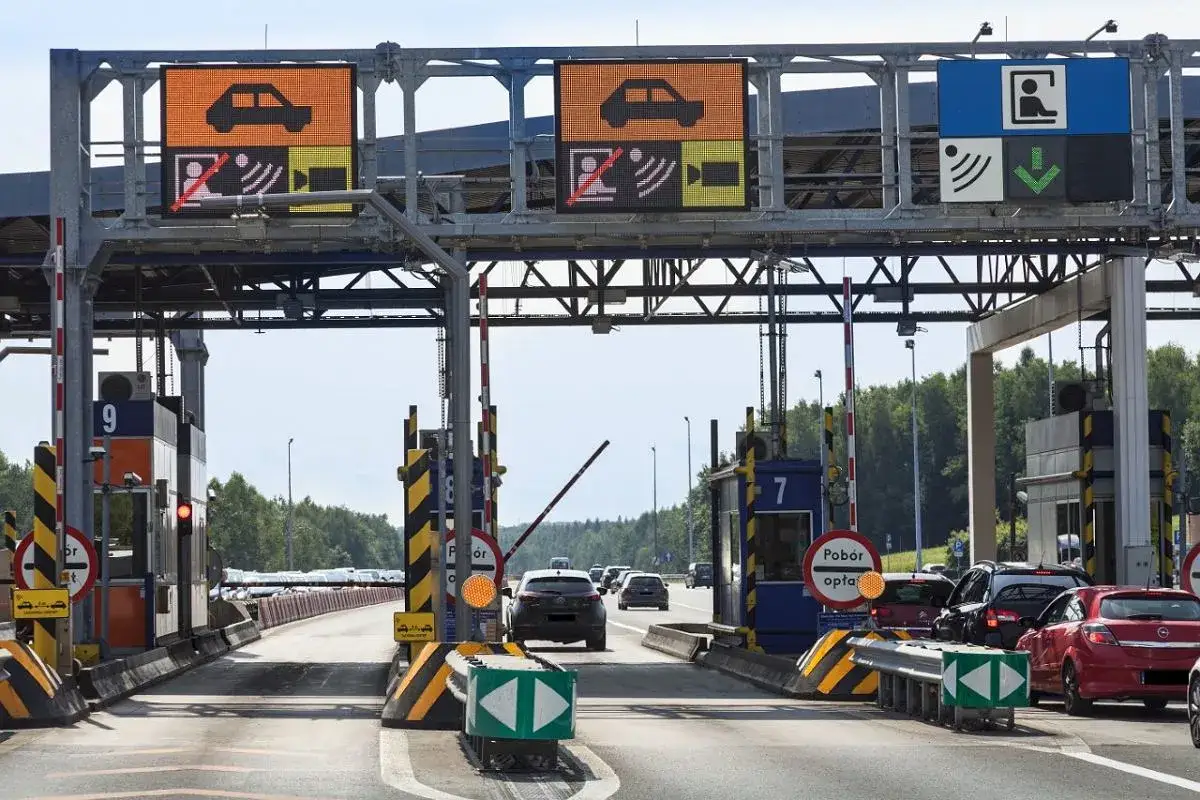 Kolejka samochodów na płatnych autostradach w Polsce. Znaki informują o opłatach i kierunku jazdy.