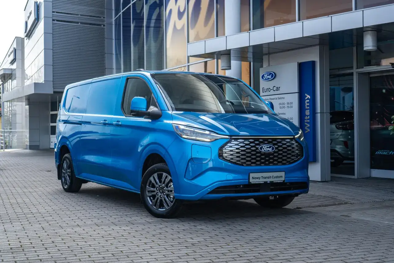 Niebieski Ford Transit Custom przed salonem. Sprawdź jego pojemność baku i wybierz się w długą podróż.