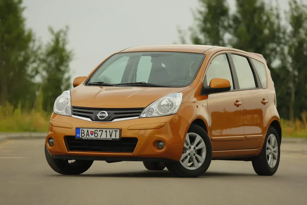 Pomarańczowy Nissan Note 1.4, idealny do miasta. Jego pojemność baku pozwala na długie podróże bez częstych postojów.