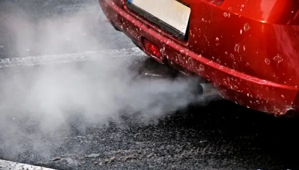 Z rury wydechowej czerwonego auta wydobywa się biały dym, jakby rozbiegany diesel próbował złapać oddech.